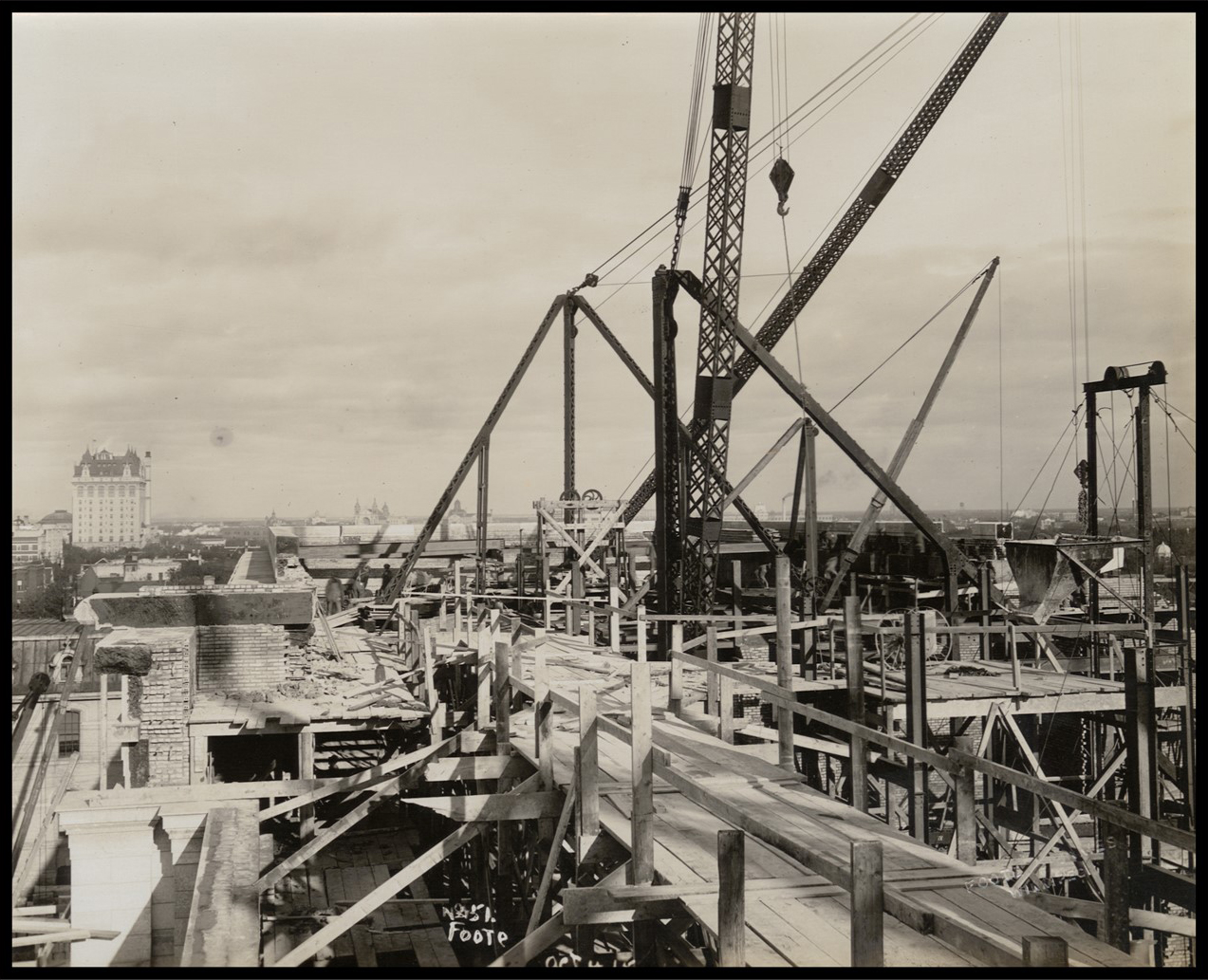 View of the constuction of the top of the building, with wood boardwalks and large steel frames and cranes throughout. 